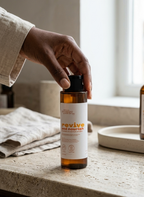 Hand holding a bottle labeled 'revive and nourish' on a countertop.