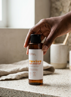 Hand holding a bottle labeled 'revive and nourish' on a countertop.