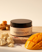 Jar of Mango Bliss Body Mousse with mango pieces and turmeric on a wooden board
